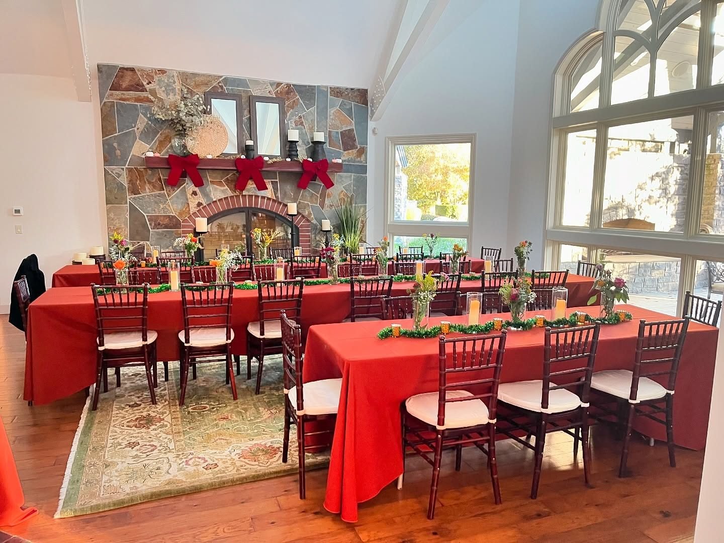 Long tables set for dinner indoors beside the stone fireplace
